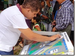 LEGENDA ACESSÍVEL - Imagem mostra Marcos Barbosa do Projeto Um Olhar para a Cidadania lendo um mapa tátil instalado na Praça Pedro II em Teresina durante o Salão do Livro do Piauí - SALIPI 2013