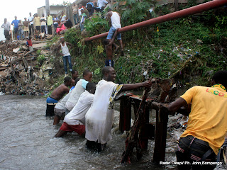 Un groupe des jeunes Kinois tente de récupérer un pont artisanal détruit par la pluie sur la rivière Basoko entre la commune de Bandalungwa et le quartier GB à Gombe, ce 03/04/2011 à Kinshasa. Radio Okapi/Ph. John Bompengo