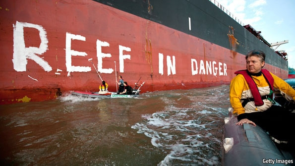 Activists paint 'Reef in danger' on the side of a ship in the port town of Gladstone, Australia. The harbour is undergoing the biggest dredging operation ever approved in Australia. From 2014, huge ships are due to load liquefied natural gas (LNG) from Curtis Island for export, mainly to Asia. Mud crabs, fish and other seafood have erupted in lesions, red spots and other signs of sickness. Getty Images via economist.com