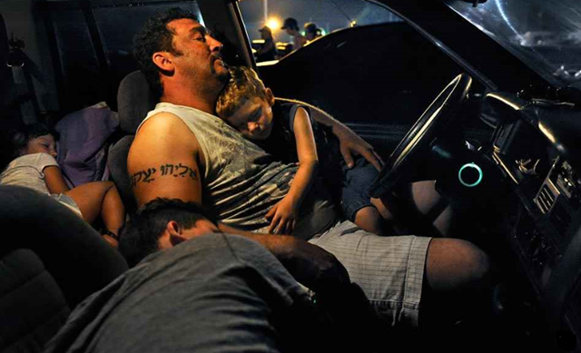 A man and his children sleep in a car outside the venue of a dental camp, hoping to get a free checkup, in Wise, Virginia. About 10.4 million working poor families -- or 47.5 million Americans -- now live near poverty. Michael S. Williamson / The Washington Post via Getty Images