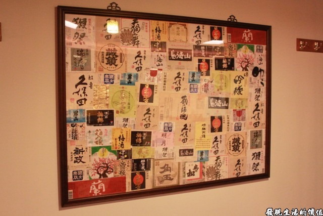 台南-花川日本料理。牆壁上的掛畫內貼滿了不同牌子的清酒標籤，算是資源回收在利用。