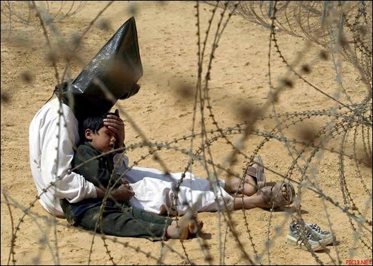 Hooded-Iraqi-prisoner-comforting-a-child-2003
