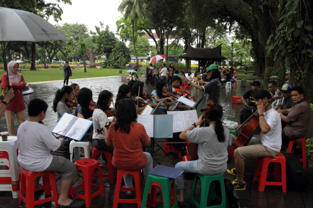 Learning to play musical instruments from street musicians at Taman Suropati, jakarta
