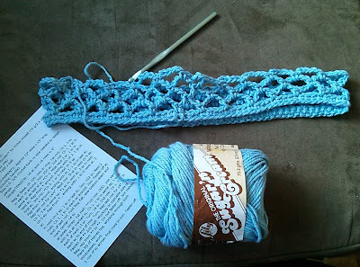 Pictured above is the beggining of a crocheted market bag with the crochet hook inserted in the work along with the skein of yarn being used and the printed pattern.