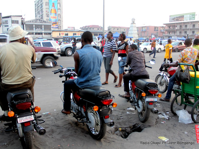 Place des artistes, Rond-point  victoire/ Kinshasa. Le trafic routier  n’est pas intense ce 2/06/2011. Quelques motards discutent en attendant l’arrivée des passagers. Ici, comme dans d’autres carrefours, les motos qui font le taxi n’ont pas toutes des plaques d’immatriculation. Ce qui n’empêche pas les motards d’exercer leur activité.