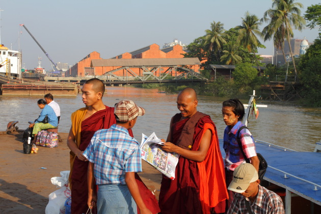Buddhist Monk reads a newspaper at Yangon's ferry terminal