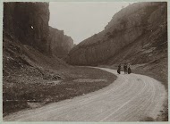 Drie wandelaars op een autoweg die tussen rotsen doorloopt