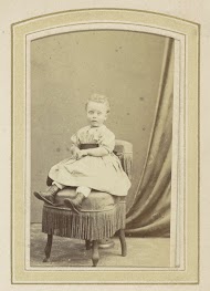 Portret van een meisje in een jurk met ceintuur op een fauteuil