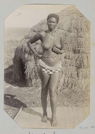 Portret van een Zoeloe vrouw met kralengordel bij woning