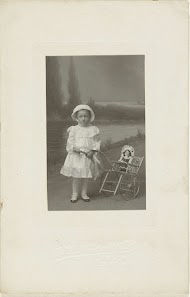 Studioportret van Theodore Kuper in witte jurk met een poppenwagen