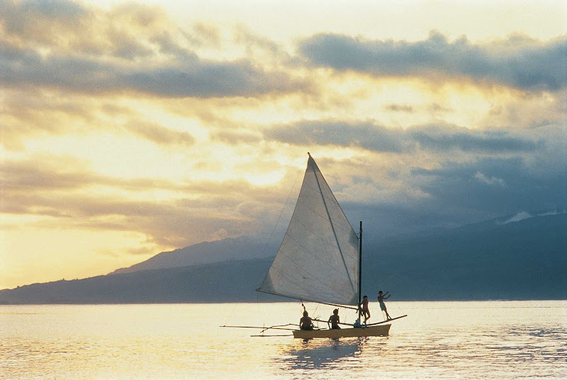 At the end of a beautiful day, enjoy the view of sailboats at sunset on Tahiti.