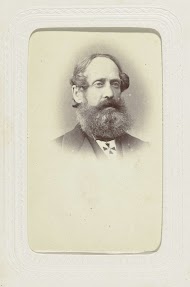 Studioportret van een man met snor en baard, om zijn nek draagt hij een insigne