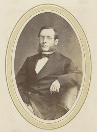 Portret van een man met een bril, bakkebaarden en een jas