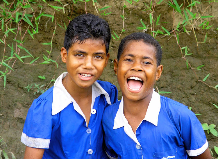 Two schoolgirls pose for a visitor in Fiji. 