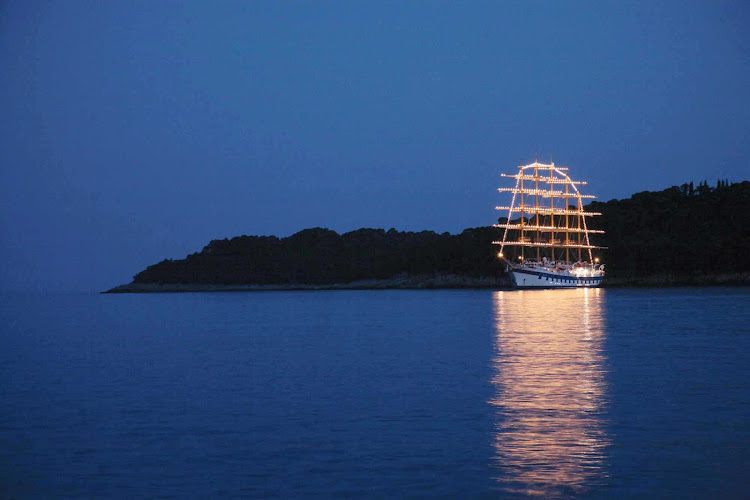 Step out onto Royal Clipper's deck at night and admire the clipper ship's beautiful lit-up five-masted sails.