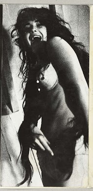 Staande vrouw met erg lang, zwart, loshangend haar en wijd open mond