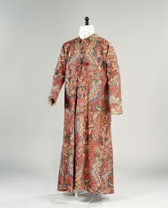 Lang mouwloos vest van sits met een rood fond, versierd met gekleurde zigzagranden, omgeven door abstracte florale motieven; voering en rug van linnen