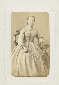 Studioportret van een vrouw aan tafel in een lange, bolle jurk