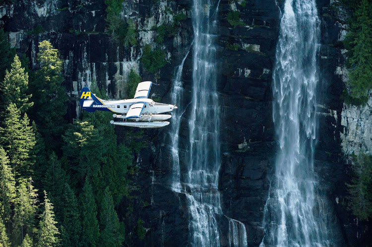 A Harbour Air Floatplane flies past waterfalls near Vancouver, British Columbia.