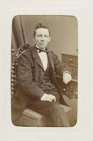 Studioportret van een man op een stoel aan een bureau