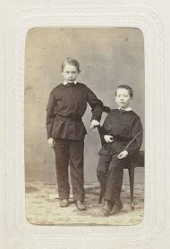 Studioportret van twee jongens in zwarte pakjes