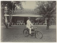 De heer Letterie in uniform op fiets in de tuin van zijn huis in Mojosari