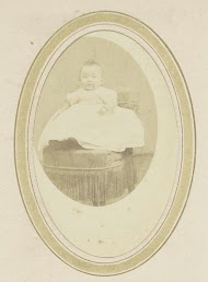 Portret van een baby in een jurk op een fauteuil