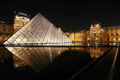 The Louvre and its iconic pyramid at night in Paris.