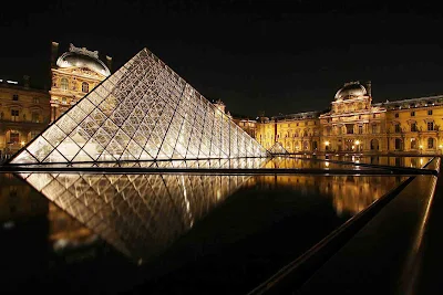 The Louvre and its iconic pyramid at night in Paris.