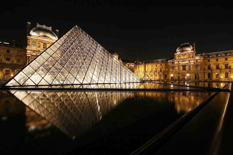 The Louvre and its iconic pyramid at night in Paris.
