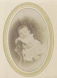 Portret van een baby in een jurk op een fauteuil