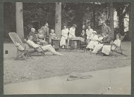 Groepsportret van de familie Kessler aan een buitentafel tijdens een kopje koffie