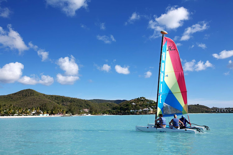 A Hobie Cat catamaran plies the waters off Jolly Beach, Antigua, in the Caribbean.