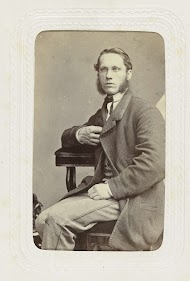 Studioportret van een zittende man met een bril en bakkebaarden