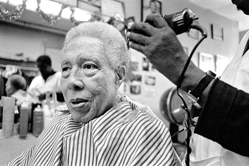 Leonard "Red" Jackson relaxes in the barber chair at Harvey's Barber Shop, in Harlem, where he has been getting his hair cut for thirty years, New York