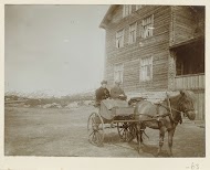 Een echtpaar  in een rijtuig voor een houten huis