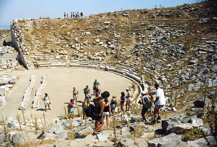 A tour group from France inspects the ruins of the ancient amphitheater on the Greek island of Delos.