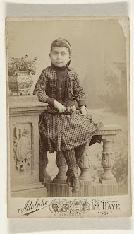 Studioportret van een meisje zittend op een balustrade tegen een achtergronddoek