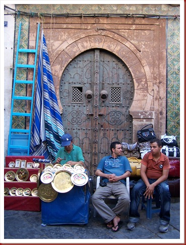 050 - Túnez, la medina. Rincón de la Rue Jamâa ez Zitouna, con un artesano del latón trabajando ante una hermosa portada.