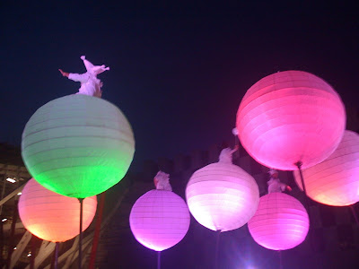 photo shows a number of giant, inflatable spheres in different luminous colours with people on them