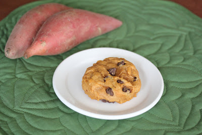 photo of a cookie on a plate with two sweet potatoes in the background