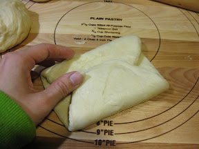 a process photo showing how the other end is folded to meet the other end of the dough in the middle of the oval