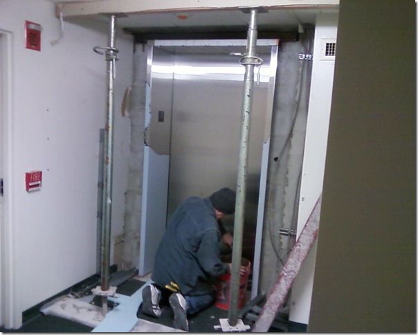 Worker installing elevator door.