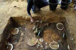 A man examines the remains of an open-air banquet shovelled underground almost 30 years ago by Switzerland's artist Daniel Spoerri as an art performance, on June 2 at Jouy-en-Josas, France. Pigs ears, smoked udders or veal lungs? French archaeologists have begun examining the leftovers.