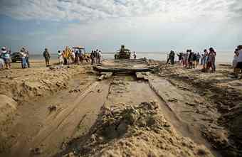Volunteers and members of the North Carolina Wildlife Resources Commission use fire hoses, hand shovels and heavy equipment to remove the sand and pull what remains of a shipwreck off the beach in Corolla, N.C. on Tuesday, April 6, 2010. The wreck could be the oldest shipwreck on the Carolina coast. (L. Todd Spencer | The Virginian-Pilot) 