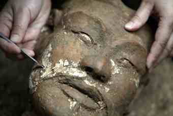 An archaeologist removes earth from the face of a newly found terracotta warrior at the excavation site inside the No. 1 pit of the Museum of Qin Terracotta Warriors and Horses, on the outskirts of Xi'an, Shaanxi province.