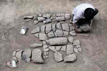 An archaeology staff member adjusts the head of a newly found terracotta warrior at the excavation site inside the No. 1 pit of the Museum of Qin Terracotta Warriors and Horses, on the outskirts of Xi'an, Shaanxi province.