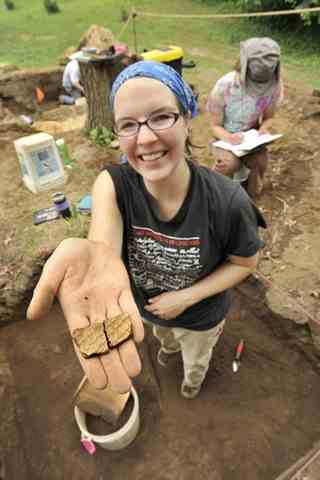 Archaeologist Lauren Schiszik displays more recent artifacts just discovered in the block she was working: two adjoining pieces of Staffordshire slipware from the Colonial era. This block was a plowed site, so the artifacts from different centuries were disturbed and mixed together.