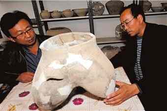 Archaeologists study an earthenware cooking pot.
