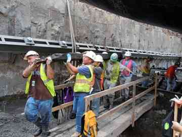 Construction workers accompanied by maritime archaeologist Warren Riess (in pink vest) move one of the vessel's timbers to safety. The ship's remains are now in the Maryland Archaeological Conservation Laboratory for further study. (Courtesy Lower Manhattan Development Corporation/AKRF)